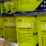 Mehrere hellgrüne Eimer des codex X-FUSION C 3-K Design Epoxi-Mörtels im Verkaufsregal bei Stolzenbach Baustoffe in Bremen.