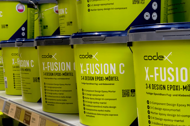 Mehrere hellgrüne Eimer des codex X-FUSION C 3-K Design Epoxi-Mörtels im Verkaufsregal bei Stolzenbach Baustoffe in Bremen.