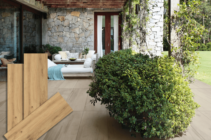 Lifestyle-Ansicht einer Terrasse mit Keramik-Bodenplatten in heller Holzoptik (Farbe Honey), kombiniert mit einer Natursteinwand, Lounge-Möbeln und Grünpflanzen. Im Vordergrund sind drei einzelne Produktmuster der Fliese abgebildet.