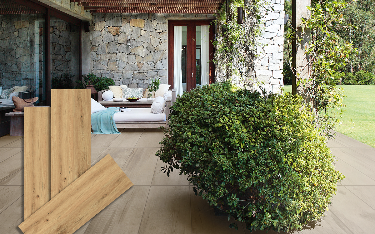 Lifestyle-Ansicht einer Terrasse mit Keramik-Bodenplatten in heller Holzoptik (Farbe Honey), kombiniert mit einer Natursteinwand, Lounge-Möbeln und Grünpflanzen. Im Vordergrund sind drei einzelne Produktmuster der Fliese abgebildet.