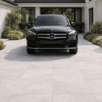 Einfahrt und Vorplatz mit Keramik-Terrassenplatten HAT-89 in grauer Natursteinoptik und einem schwarzen Auto.