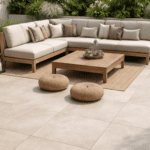 Modern gestaltete Terrasse mit Keramik-Platten HAT-90 Cream im Format 90x90 cm vor einer Gartenlounge.